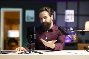 Close up shot of cellphone assessed by tech expert in studio talking about parts used inside. Focus on phone reviewed by entertainer in blurry background for technology internet channel photo