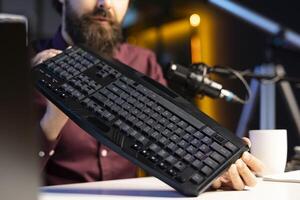 Close up shot of gaming keyboard reviewed by influencer in studio. Internet show host filming electronics haul, presenting bluetooth wireless computer peripheral to subscribers photo