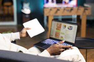 Freelancer working from home doing math calculations using statistical data financial graphs. Remote worker comparing company profit using business charts economic figures, writing on notepad photo