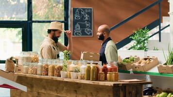 Farmer supplies zero waste eco store with freshly harvested fruits and vegetables, bringing crates filled with new products to local vendor. Storekeeper and farming business owner shake hands. photo