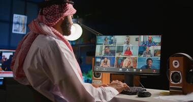 Remote Arab professional holding q and a session with webinar participants via conference meeting in cozy apartment. Online call host engaging in online discussions with trainees photo