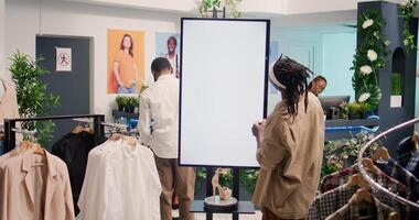 Customer in high tech thrift shop using digital screen to find perfect outfit. African american client in second hand clothing store doing shopping using augmented reality kiosk photo