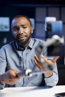 Influencer reviewing selfie stick, expressing dissatisfaction with subpar quality. Content creator shooting for online channel, displeased with low quality smartphone holder photo