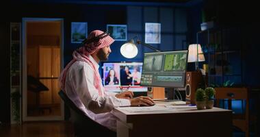 Muslim colorist wearing headphones while editing project, creating film montage, working with images and sounds. Man using cutting technology to process movie on PC workstation photo