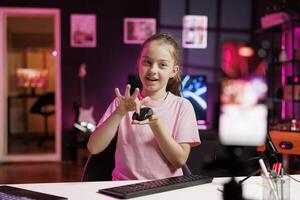 Gen Z internet star in studio reviewing gaming mouse in front of professional camera in personal studio. Happy kid filming electronics haul, showcasing Bluetooth computer peripheral to audience photo