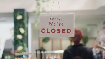 Worker closing down store in order to do restocking in elegant high end fashion boutique. Employee adding closed sign on clothing store door to be able to add stylish garments from new collection photo