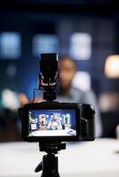 Focus on professional production camera used for capturing footage of tech enthusiast in blurry background filming smart light bulb review for online audience, showcasing home automation system photo