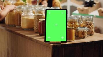 Mockup tablet with empty copy space used as commercial sign in zero waste supermarket, close up. Isolated screen device acting as promotional message in food store with biodegradable packaged products photo