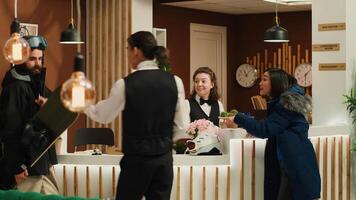 Active couple in winter outerwear stands in hotel reception during holiday, receptionists greeting tourists. Visitors with skiing and snowboarding gear ready for alpine adventures at ski resort. photo