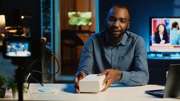 BIPOC tech content creator filming product unboxing of newly released smartphone, urging audience to purchase it too. Internet star payed by sponsor to show phone to subscribers photo