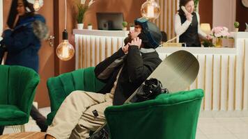 Young couple with sliding gear on sofa sitting in lounge area. Man and woman preparing their equipment to go skiing and snowboarding together using helmets, alpine extreme sport. photo