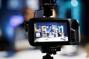 Focus on professional production camera used for capturing footage of audio engineer in blurry background filming tech reviews for online audience, showcasing Bluetooth portable speaker photo