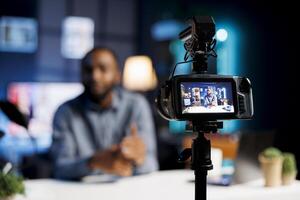 Professional camera capturing footage of streamer chatting with online audience. Trending content creator in blurry background discussing with fans filming with high quality recording tech photo