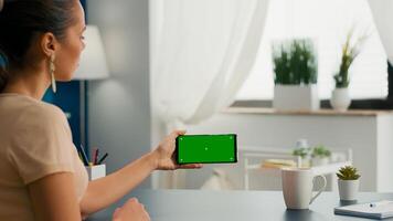 Business woman holding phone with mock up green screen chroma key for copy space sitting on office desk. Social media influencer browsing on internet using isolated gadget photo