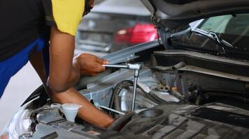 Precise mechanic in car service uses wrench to tighten nuts after fixing vehicle parts. Repair shop employee utilizing professional tools to make sure automobile is functioning errorless, close up photo
