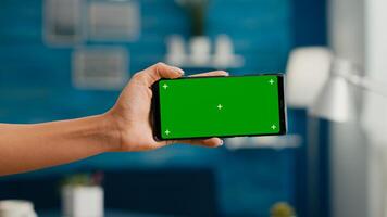 Close up of woman hands holding horizontal mock up green screen chroma key smartphone. Business woman using isolated phone for browsing social networks sitting on office desk photo