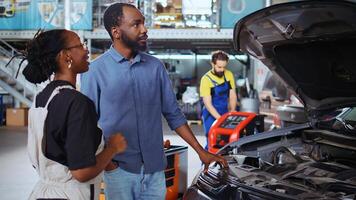 Certified technician in auto repair shop uses augmented reality technology to visualize car performance parameters. Woman in high tech garage using ar hologram to show client proposed vehicle upgrades photo