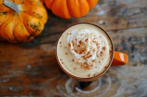 Steaming pumpkin spice latte sitting on rustic wooden table with pumpkins photo