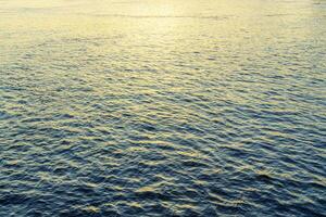 The texture of ripples on the water in a pond illuminated by the setting sun. Natural background. photo