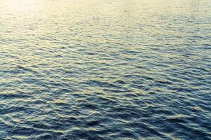 The texture of ripples on the water in a pond illuminated by the setting sun. Natural background. photo