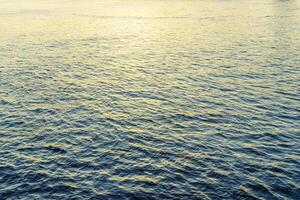 The texture of ripples on the water in a pond illuminated by the setting sun. Natural background. photo