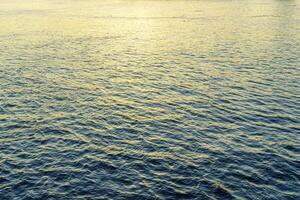 The texture of ripples on the water in a pond illuminated by the setting sun. Natural background. photo