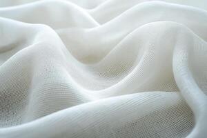 Soft, white fabric with a delicate, sheer texture, gently draped in smooth waves, creating an elegant and airy look photo