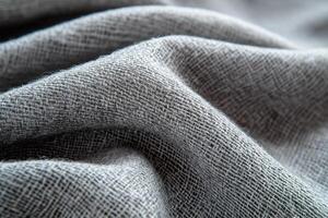 Gray woven fabric with a textured, grid-like pattern, draped softly to highlight its intricate weave and detail photo