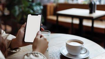 Mockup image blank white screen cell phone hand holding texting using mobile on desk at coffee shop. background empty space for advertise text. photo
