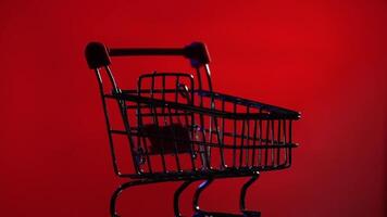close-up of a silhouette empty shopping cart from supermarket rotates on red video