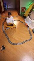 vertical boy controls a toy train on railway using tablet, remote control video