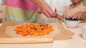 Parent and child cooking together adding blueberries to dessert video