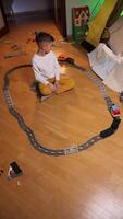 vertical boy plays with a toy railroad while sitting on floor in his room video