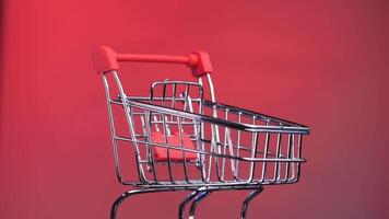 close-up empty shopping cart from supermarket rotates on red, pink background video