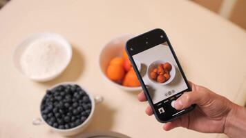 Person using smartphone to take a picture of fruit and baking ingredients video