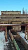 A row with containers on the railway line stand at the entrance to the tunnel on the background other rows in the terminal station in the winter season. Aerial view. Vertical video