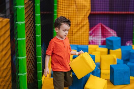 A boy child is playing in a game entertainment nursery. He plays with soft large cubes. Active pastime in the amusement park. photo