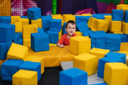 A boy child is playing in a game entertainment nursery. He plays with soft large cubes. Active pastime in the amusement park. photo