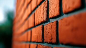 Angled closeup of a rough brick wall painted in burnt orange texture highlighting brick seams and minor surface flaws giving a warm and rustic appeal photo