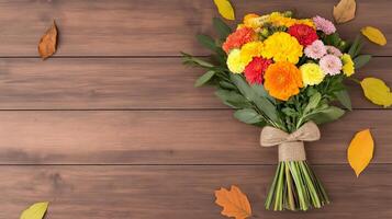 Overhead view of an autumn bouquet with a mix of marigolds asters and goldenrods tied with a burlap ribbon placed on a wooden table with scattered fall leaves around photo
