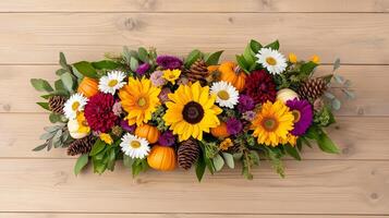 Overhead view of an autumn centerpiece with a mix of seasonal flowers like sunflowers mums and asters arranged with pinecones and mini pumpkins on a rustic wooden table photo