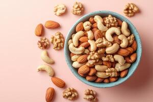 Assorted Nuts in Blue Bowl on Pink Background - Healthy Snack Variety of Almonds, Cashews, and Walnuts photo