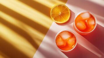 Refreshing Summer Orange Drink with Ice Cubes in Sunlight on Yellow and Pink Background photo