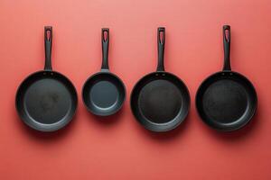 Set of Four Black Frying Pans on Red Background - Modern Cookware Collection for Kitchen and Culinary Use photo