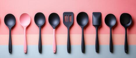 Modern Kitchen Utensils Set on Colorful Background - Black and Pink Cooking Tools in a Row photo