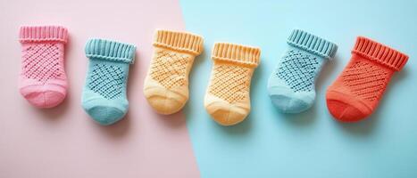 Colorful Knitted Baby Socks Arranged in a Row on Pastel Pink and Blue Background photo