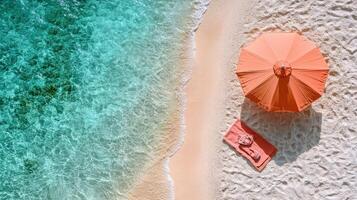 Aerial View of Pristine Beach with Turquoise Water, Orange Umbrella, and Towel on Sandy Shore photo