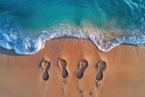 Footprints in the Sand by the Ocean Shore with Turquoise Waves Crashing on a Sunny Day photo