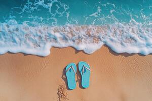 Pair of Blue Flip-Flops on Sandy Beach with Gentle Ocean Waves in Background photo