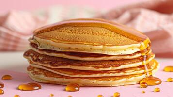 Stack of Fluffy Pancakes Drizzled with Golden Maple Syrup on a Pink Background photo